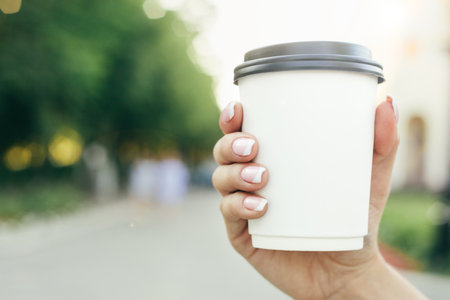 hand holding paper cup of coffee on natural morning background. Horizontal viewの写真素材