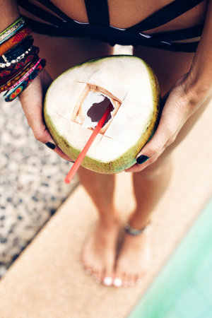 portrait of cute girl with coconut cocktail in the tropical pool. Horizontal. Outdoors lifestyle