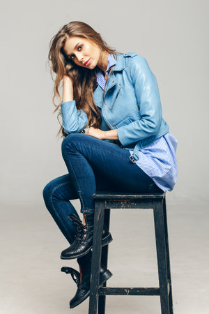 Pretty girl with long wavy hair . Fair-haired model with curly hairstyle and fashionable makeup . Female model over grey backgroundの写真素材