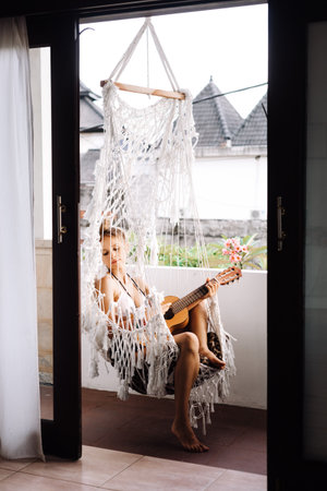 lifestyle summer portrait of woman playing ukulele in hammockの写真素材