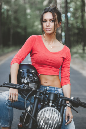 The girl sitting on a motorcycle standing near the road.
