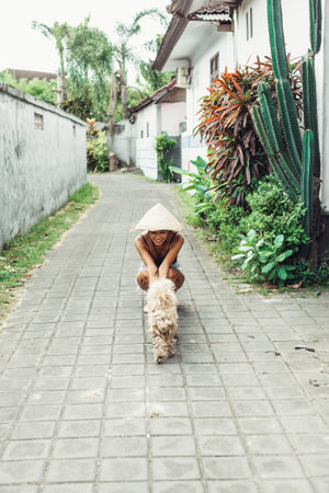 young beautiful happy positive woman on summer vacation in asia, having fun with dogの写真素材