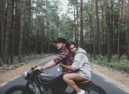 Young Caucasian couple on a motorcycle caferacer on the forest road.の写真素材