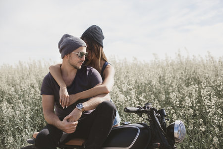 Young romantic couple in a field on a motorcycle.の写真素材
