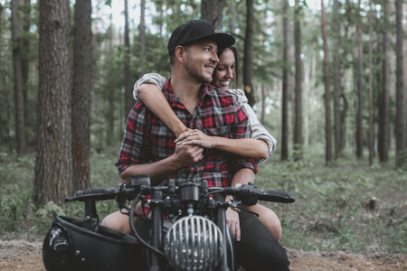 Young Caucasian couple on a motorcycle caferacer on the forest road.の写真素材