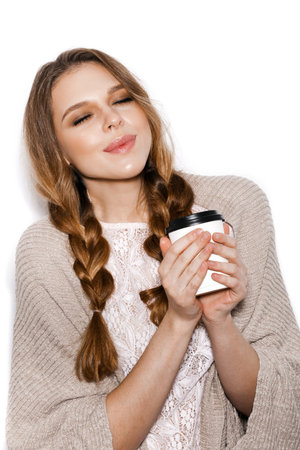 Cheerful young female model holding a paper to-go cup of coffeeの写真素材
