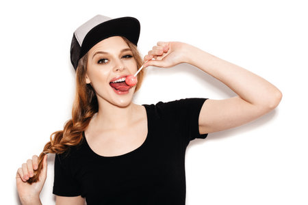 Young beautiful girl with lollipop in her mouth. Studio shoot on white background not isolatedの写真素材