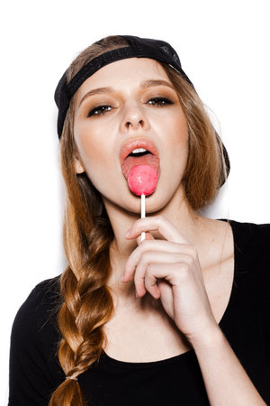 Young beautiful girl with lollipop in her mouth. Studio shoot on white background not isolated