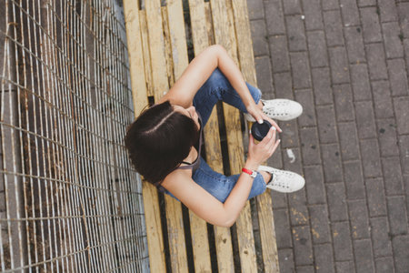 Girl drinking coffee from a paper cup in the morning. View from above, overheadの写真素材