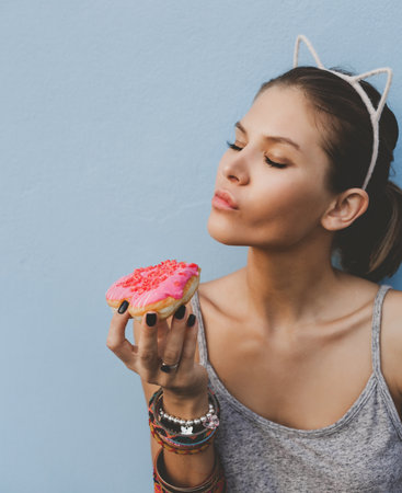 Woman holding tasty donut. Outdoors lifestyle portrait of pretty girlの写真素材