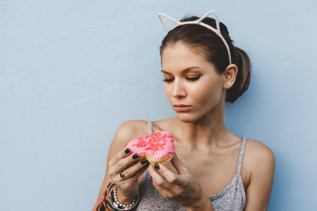 Woman holding tasty donut. Outdoors lifestyle portrait of pretty girlの写真素材