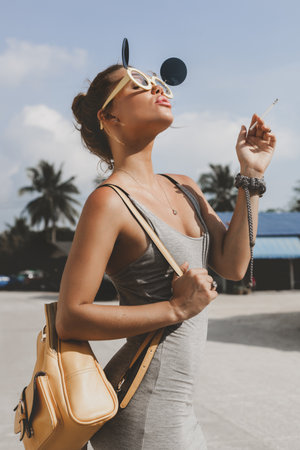 Outdoors lifestyle portrait of a beautiful young woman smoking cigaretteの写真素材