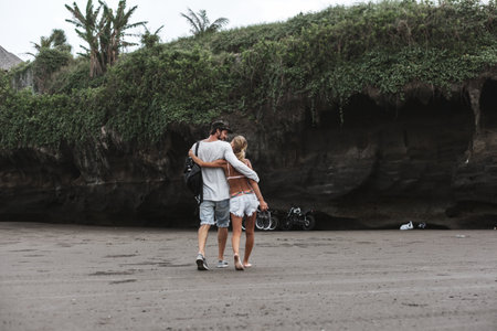 Young couple walking along lonely beach at sunsetの写真素材