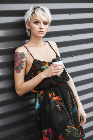 Outdoors lifestyle portrait of young female drinking coffeeの写真素材