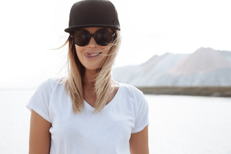Young sexy swag girl. Outdoor lifestyle portrait of female in sunglasses and black cap. Summer photo toned style Instagram filtersの写真素材