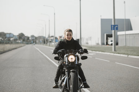 Biker Woman Girl ridding a chopper motorcycle on an empty city roadの写真素材