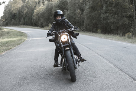 Young biker woman riding chopper motorbike on forest roadの写真素材