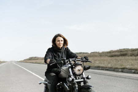 Biker Woman Girl ridding a chopper motorcycle on an empty city roadの写真素材