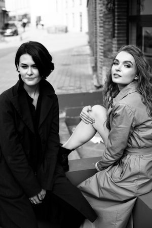 friendly nice beautiful women sitting on the edge outside nearby the brick wallの写真素材