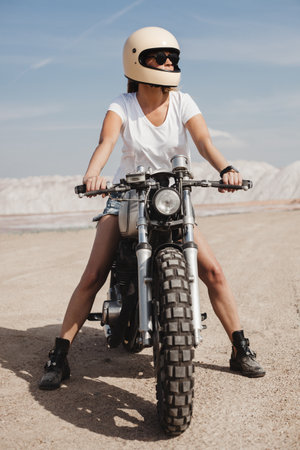 beautiful sexy woman sitting on the caferacer, mountains as background, adventure moodの写真素材