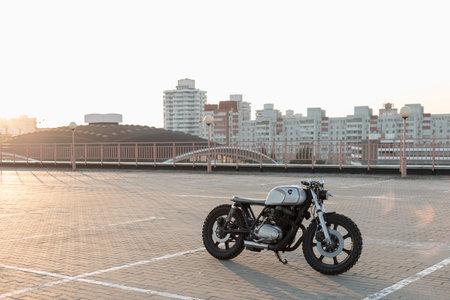 Custom vintage motorcycle cafe racer on empty rooftop parking lot during sunset. Side view. Hipster lifestyle, student dreamの写真素材