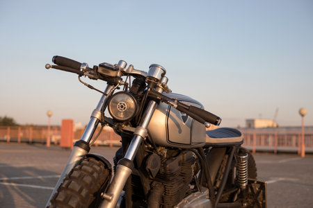 Custom motorcycle cafe racer on empty rooftop parking lot during sunset. Front view. Hipster lifestyle, student dreamの写真素材
