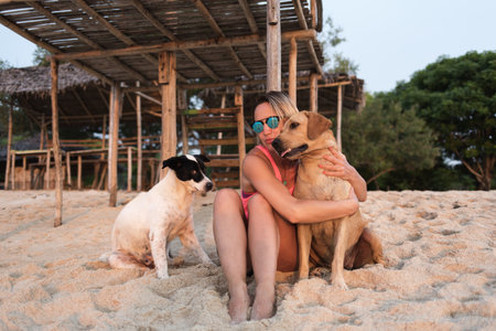 tender playful woman or girl hug her dog, chilling on sunny sandy beach, enjoying warm weather, sun and lifeの写真素材