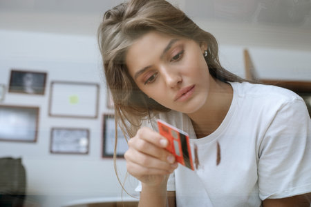 Young woman making lines with make-up sniffing glitter (imitation) on glass table. Conceptual art...