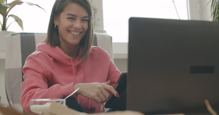 Attractive woman using her laptop computer and doing meeting or web conference from home. Freelance female model girl working out of office.の写真素材