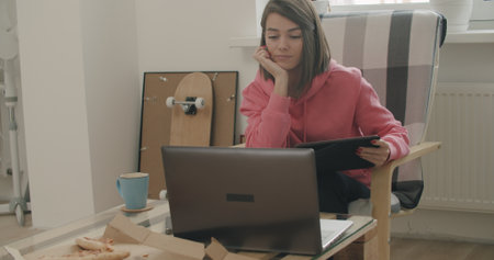 Attractive woman using her laptop computer and doing meeting or web conference from home. Freelance female model girl working out of office.の写真素材