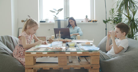 Brother and sister draw and play. Mother feeds children. Family having lunch. Fast food, pizza . Young woman works from home. Self-isolationの写真素材