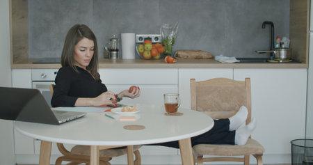 Woman designer working with papers sitting in kitchen at homeの写真素材