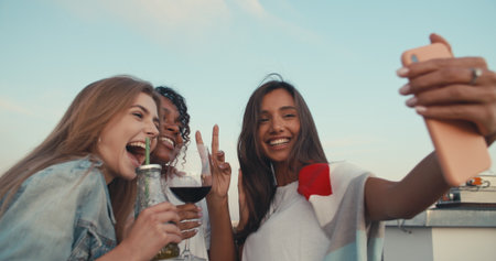 Group of young people having fun at a rooftop party, taking selfie