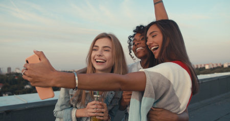 Group of young people having fun at a rooftop party, taking selfieの写真素材