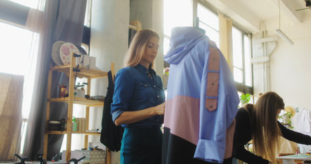 Young female tailor workers, modeller and stylist discussing clothing design in workshopの写真素材