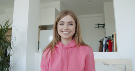 young woman working at home. Girl speaking looking at camera talking making video chat or conference call. Happy female smilingの写真素材