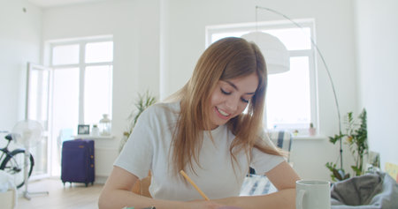 Smiling young woman working at home. Girl speaking looking at camera talking making videochat or conference call, Happy female greeting waving handの写真素材