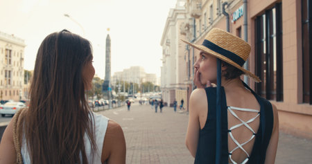 Two young girls in a good mood walking through the city streetsの写真素材