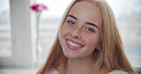 Close-up of young caucasian red haired teenage girl smiling laughing on window backgroundの写真素材