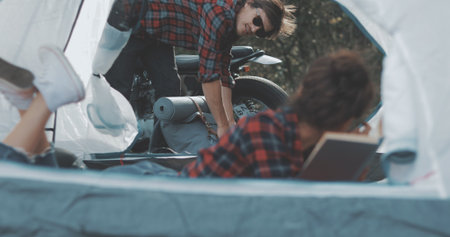 Young tourists couple in love on vacation in forest. Hiker girl reads book in camping tent. People living healthy active lifestyleの写真素材