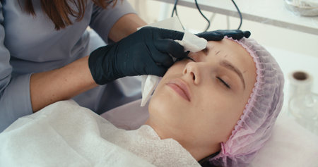 Microblading eyebrows work flow in a beauty salon. Woman having her eye brows tinted. Semi-permanent...
