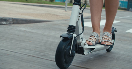 Close-up of legs of woman ride on electric kick scooter