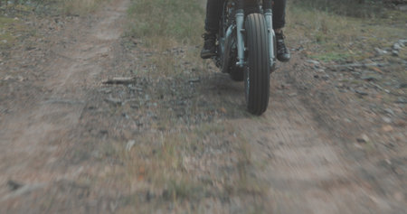 Young rider driving vintage classic custom motorcycle on forest road. Tourist with backpack on back goes to rest in campの写真素材