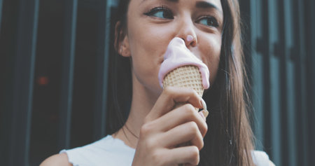 Closeup of a young girl in a white T-shirt holds a waffle cone with melt ice cream
