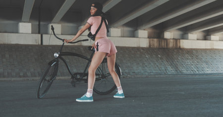 Young girl dancer dancing with black bike on urban background
