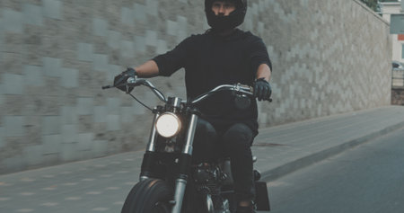 Motorcyclist drives on a motorcycle on the road in city. Biker rides a vintage custom motorbike from 1970s . Urban lifestyle sceneの写真素材