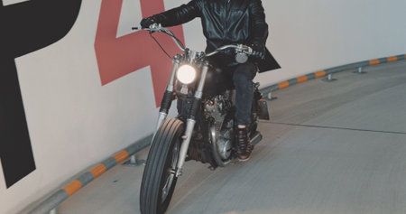 Motorbiker riding on a motorcycle in the parking lot in the city. Biker rides a vintage custom...