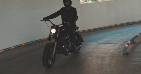 Motorbiker riding on a motorcycle in the parking lot in the city. Biker rides a vintage custom motorbike from 1970s in the garageの写真素材