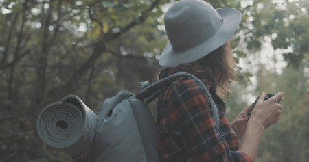 Young man and woman hiking in forest. Hiker camping in woods. Tourist couple walking by stream. Girl makes photoの写真素材