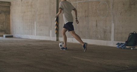Teenager girl football soccer player practicing tricks, kicks and moves with ball inside empty...
